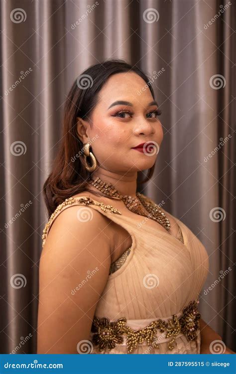 An Asian Woman Wearing A Brown Dress While Attending A Prom Night At