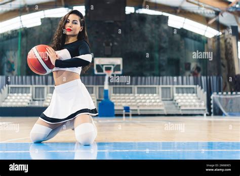 A Young Athletic Cheerleader Sitting On Her Knees On A Basketball