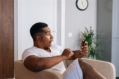 Homem afro americano espantado sentado em uma poltrona confortável e