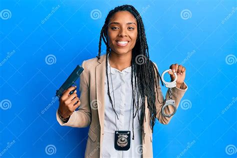 African American Police Woman Holding Gun And Handcuffs Smiling With A