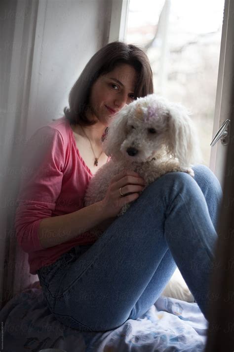 Beautiful Girl Looking At Camera With A White Dog On Her Lap By