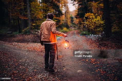 A Man With A Lantern At A Crossroads In The Woods High Res Stock Photo