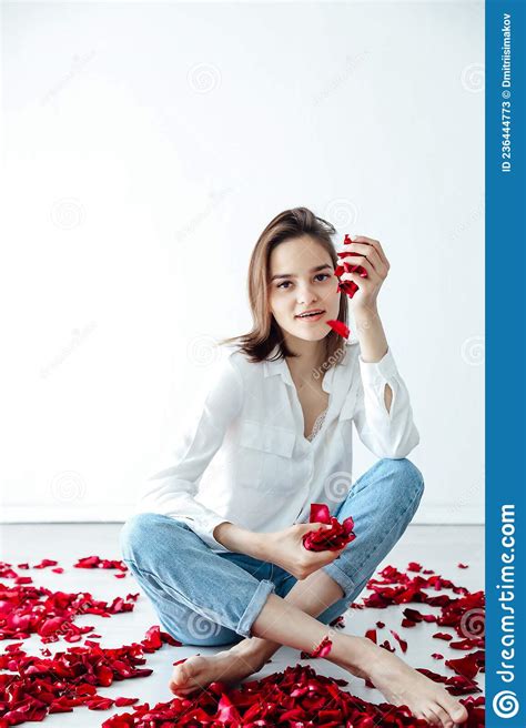 A Beautiful Woman Sits In The Petals Of Red Rose Flowers Stock Image