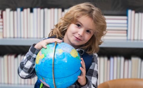 Niño de escuela mirando el globo en la biblioteca de la escuela