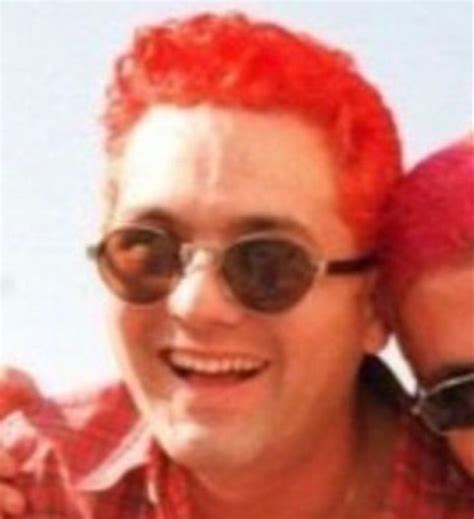 A Man With Red Hair And Sunglasses Is Holding His Arm Around Another