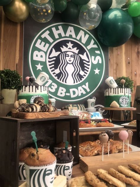 A Table Topped With Cakes And Cupcakes Next To A Starbucks Sign