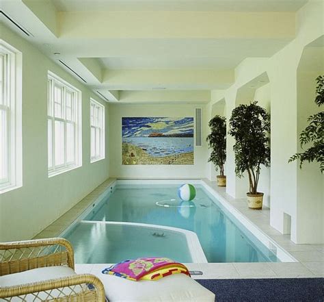 an indoor swimming pool with wicker chairs and potted plants