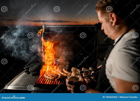 Professional Man Chef Using Tongs Gently Flips Pieces Of Meat On