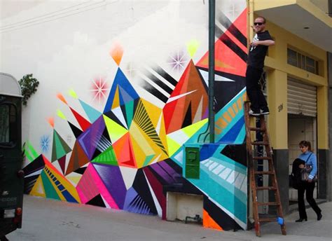 A Man Is Painting A Mural On The Side Of A Building