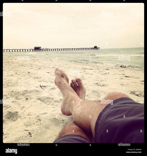 Person laying on beach. Feet in sand, Naples, Florida Stock Photo - Alamy