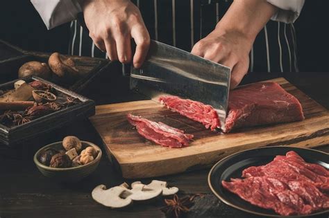 Un Chef Corta La Carne En Una Tabla Para Cortar Foto Premium