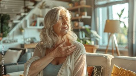 Foto De Mature Woman Relieving Shoulder Pain With Ice Pack In Modern Cozy Living Room Setting Do