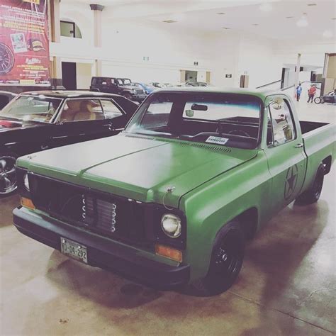 An Old Green Pick Up Truck Parked In A Showroom Next To Other Classic Cars