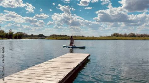 A Girl In A Swimsuit Swims On A Sap Board In The River Nice Sunny Day