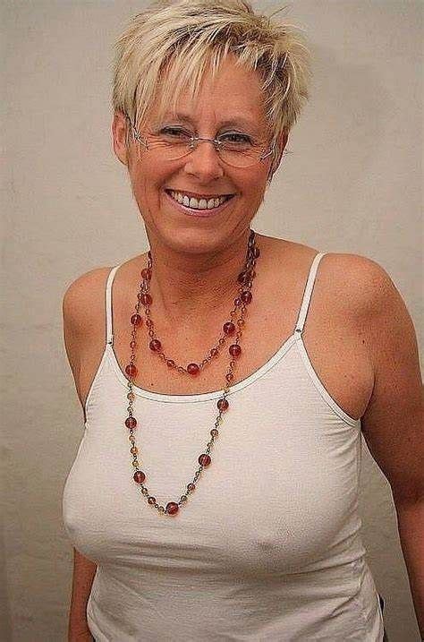 A Woman With Glasses And A Necklace On Her Neck Smiling At The Camera