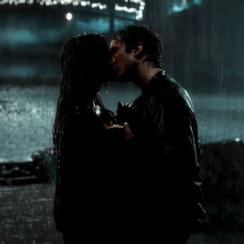 A Man And Woman Kissing In The Rain At Night With City Lights Reflected