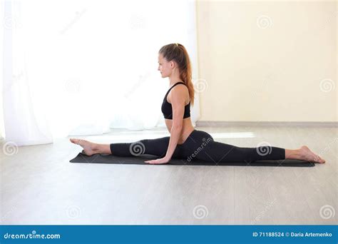 Woman Stretching Legs In Splits Position In Bright Room Stock Photo