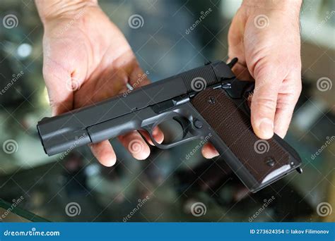 Gunsmith Shop Assistant Demonstrates Black Pistol In Hands Stock Photo