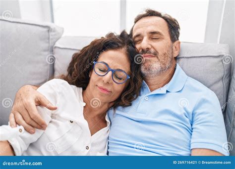 Man And Woman Couple Hugging Each Other Relaxed On Sofa At Home Stock