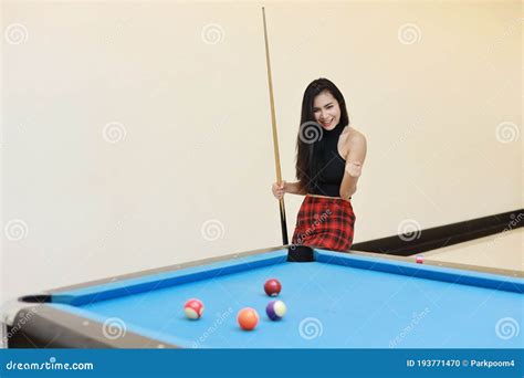 Beautiful And Asian Woman In Black Dress Playing Billiard Or Snooker On Blue Pool Table With