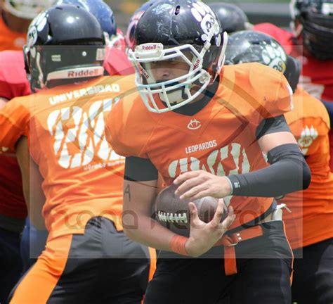 A Football Player Is Holding The Ball In His Hands While Other Players