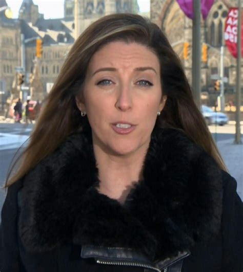 a woman with long hair wearing a black jacket and fur collar standing ...