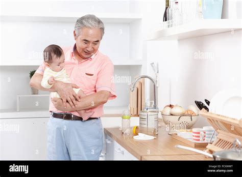 Old man taking care of a baby in the kitchen Stock Photo - Alamy