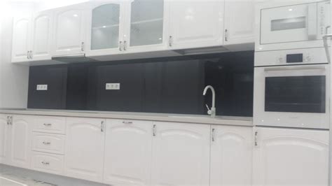 A Kitchen With White Cabinets And Black Backsplashes On The Counter Top