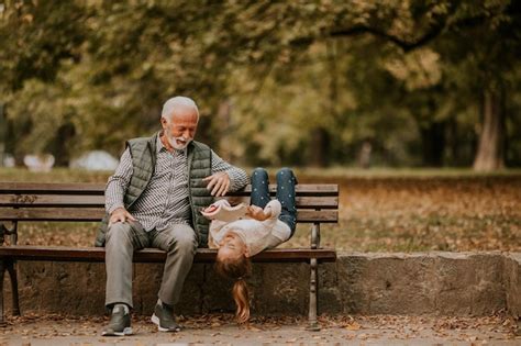 Abuelo pasando tiempo con su nieta en un banco en el parque el día de