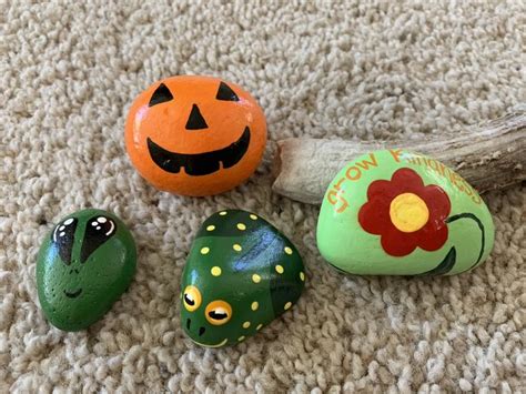 Three Painted Rocks Sitting On Top Of A Carpet Next To A Tree Branch