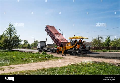 Worker Operating Asphalt Paver Machine During Road Construction And