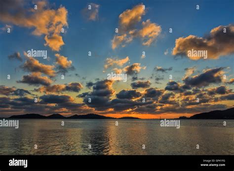 Partly cloudy sunset mountain reflections sea colors Stock Photo - Alamy