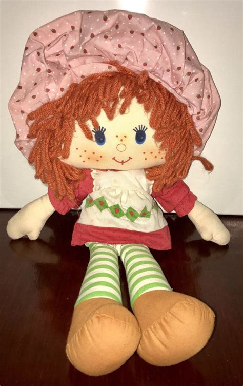 A Doll With Red Hair Sitting On Top Of A Wooden Table