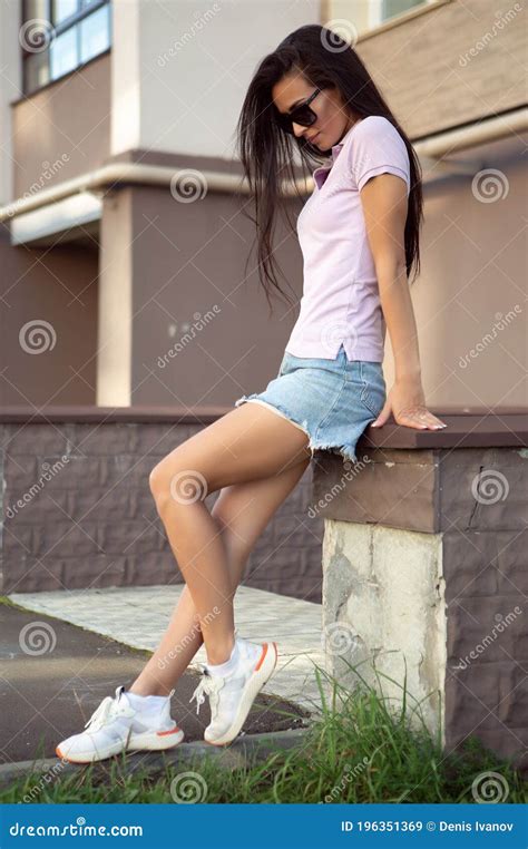 Stunning Young Woman Posing Outdoors Sitting On A Stone Bench Stock