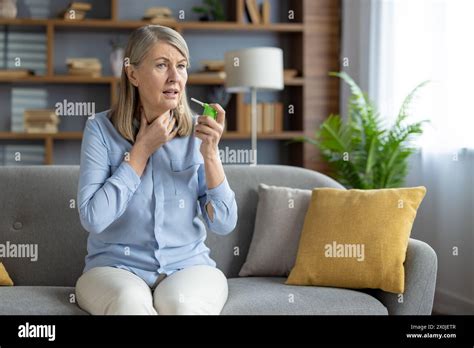 Mature Woman Experiencing Sore Throat Using A Medicinal Throat Spray