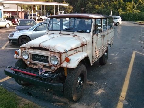 An Old Rusted Out Truck Is Parked In A Parking Lot With Other Cars Behind It