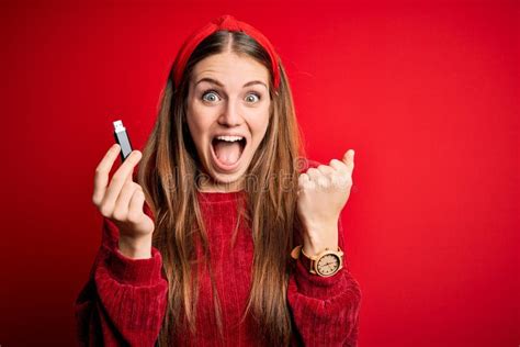 Young Beautiful Redhead Woman Holding Usb Memory Over Isolated Red Background Screaming Proud