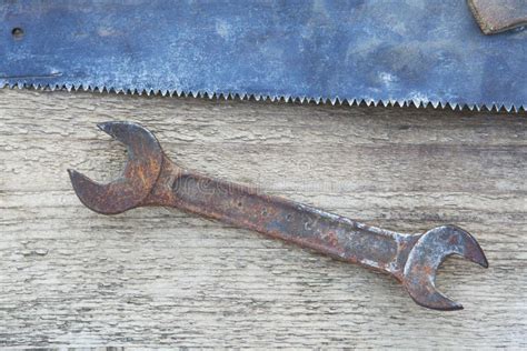 Old Rusty Wrench And Detail Of Hand Saw On A Wooden Background Stock