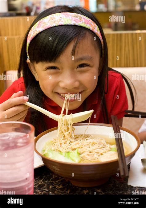 Chinese Girl Eating Shrimp Wonton And Noodle Soup With Spoon And