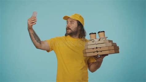 Delivery Man In Yellow Uniform Holding Pizza Boxes And Coffee Taking A