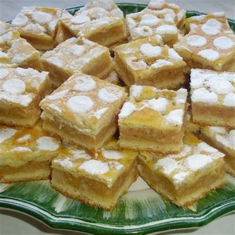 A Green Plate Topped With Lots Of Desserts On Top Of A White Tablecloth