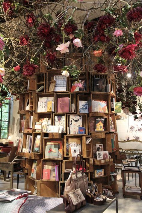 There Is A Book Shelf With Many Books On It And Flowers Hanging From