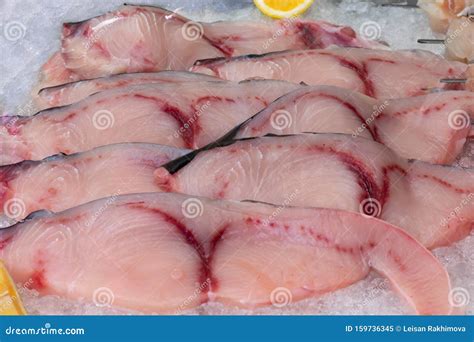 Raw Fresh Sliced Fish Filet With Lemon Pieces On The Ice In The