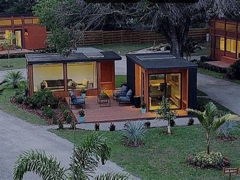 Two Tiny Houses In The Middle Of A Yard With Grass And Trees Around