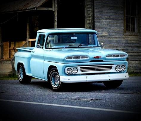 an old blue pickup truck parked in front of a wooden building on the ...