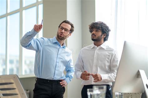 Two Businessmen Looking Busy While Discussing Project In The Office