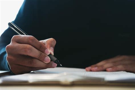 Premium Photo Midsection Of Man Writing In Book On Table