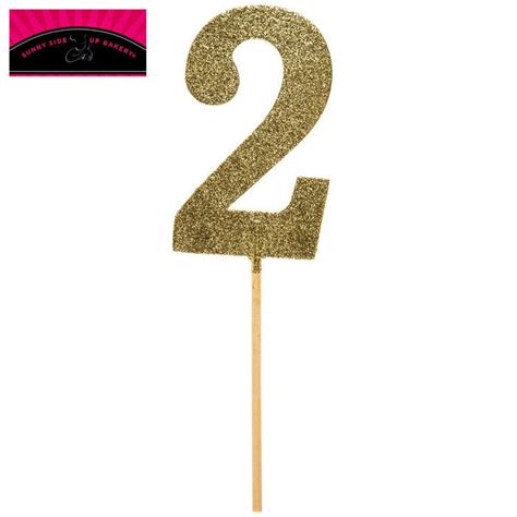 A Gold Glitter Number Two Cake Topper On A Stick