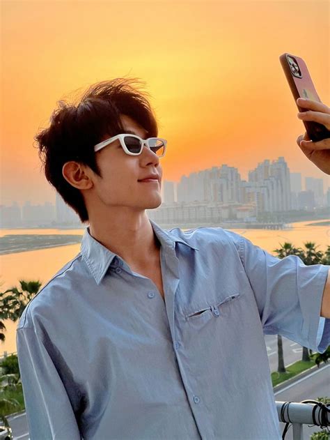 A Man Taking A Selfie With His Cell Phone In Front Of An Orange Sky