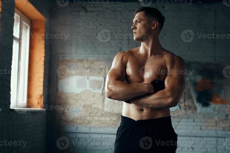 hombre musculoso guapo manteniendo los brazos cruzados mientras está de